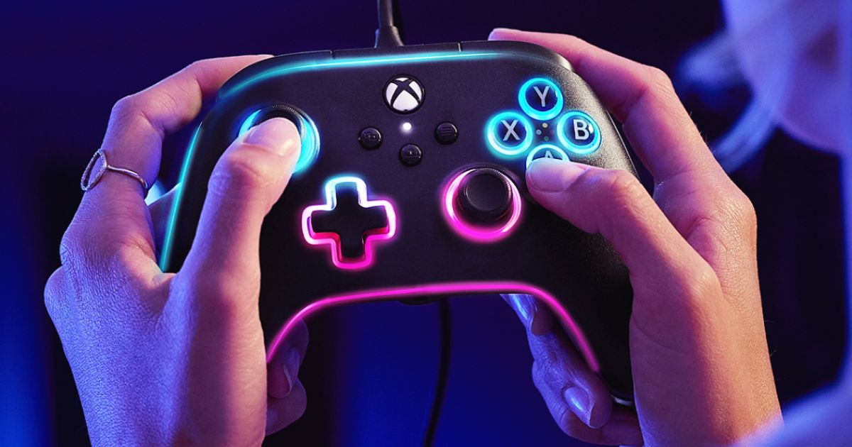 Someone holding a black wired Xbox controller with light blue and pink RGB lighting around all the trim.