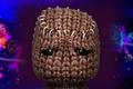 Sackboy from LittleBigPlanet looks upset with the Dreams game's key art in the background