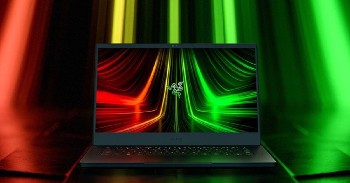 A Razer gaming laptop sits against a green and red neon background