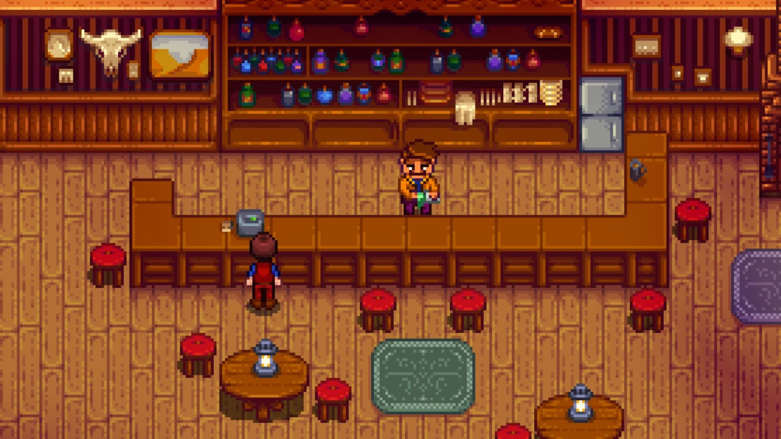 Stardew Valley, Stardrop Saloon. The player is stood at the till on the long wooden bar. The bartender, Gus, is stood behind the bar cleaning a glass.