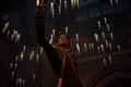 The player character holding up a cup in the Great Hall in Hogwarts Legacy