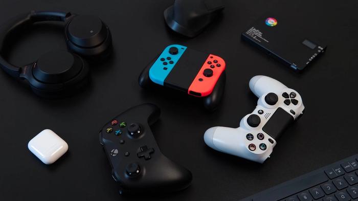An Xbox, PlayStation, and Nintendo Switch controller on a black background.