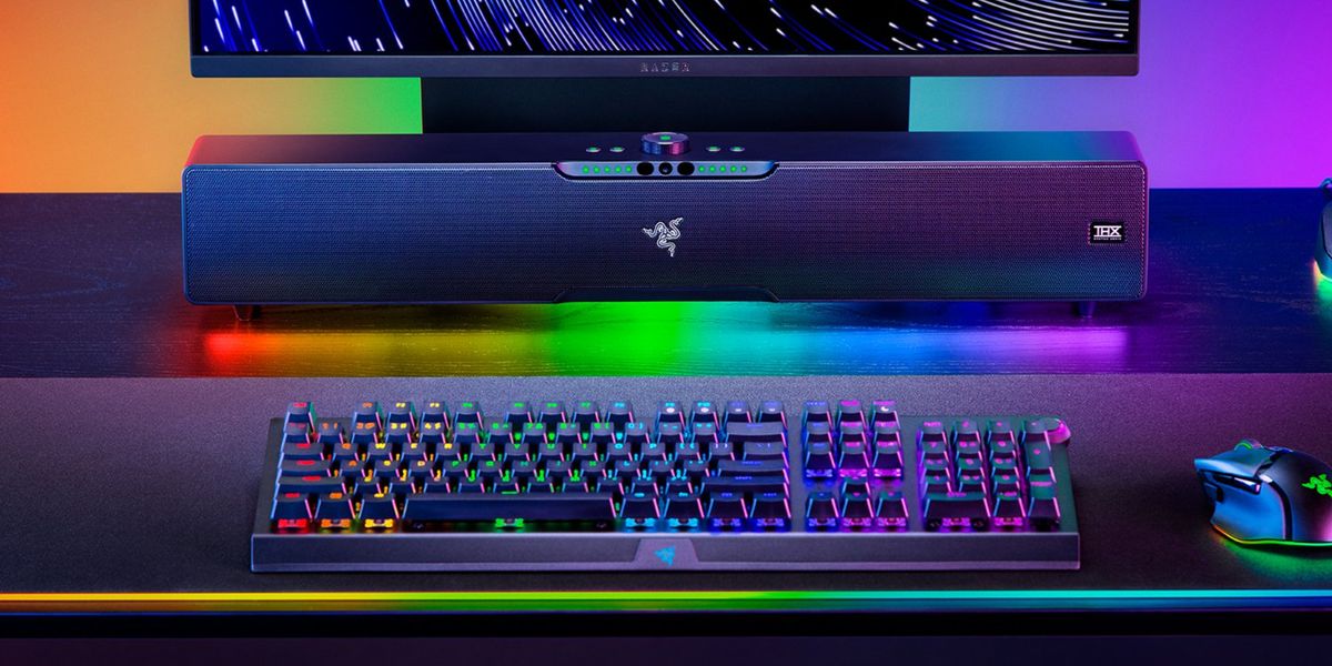 Image of a black soundbar surrounded by RGB lighting sat at a desk with a monitor, keyboard, and mouse.