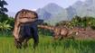 Jurassic World Evolution 2 Two Velociraptors roaming around in the wild. One Velociraptor is in the foreground looking at the camera. The second Velociraptor is stalking something in the background.