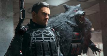 A characterr in black armor holding a gun in Modern Warfare III with a grey wolf with red eyes behind them.