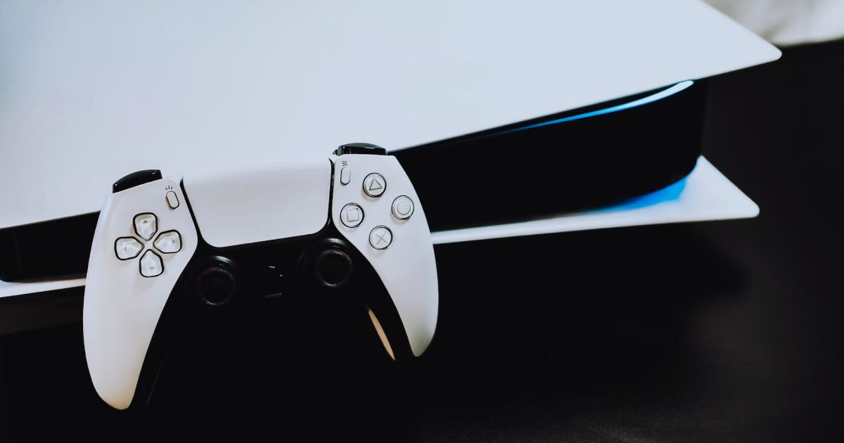 A close-up of the white and black PlayStation remote leaning against a PS5.