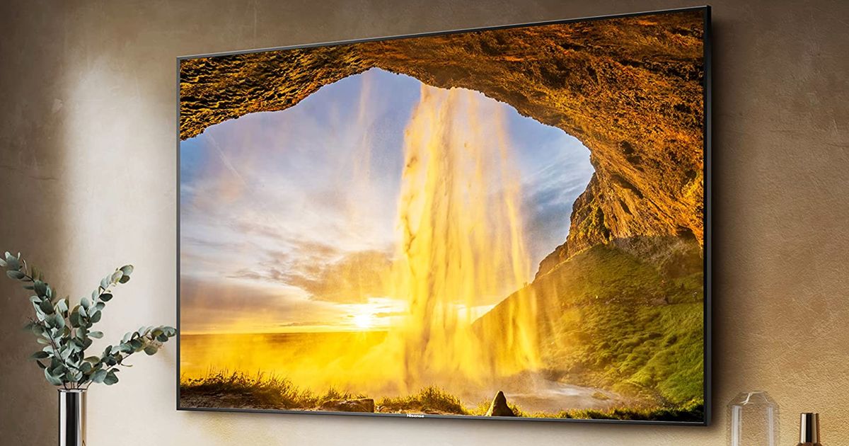 A near-frameless TV mounted to a wall with a sunset shining into a cave image on the display.