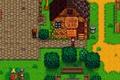 Stardew Valley. The player is outside Stardrop Saloon in Spring. The saloon is a building made out of wood and logs. There is a stone path leading up to the saloon.