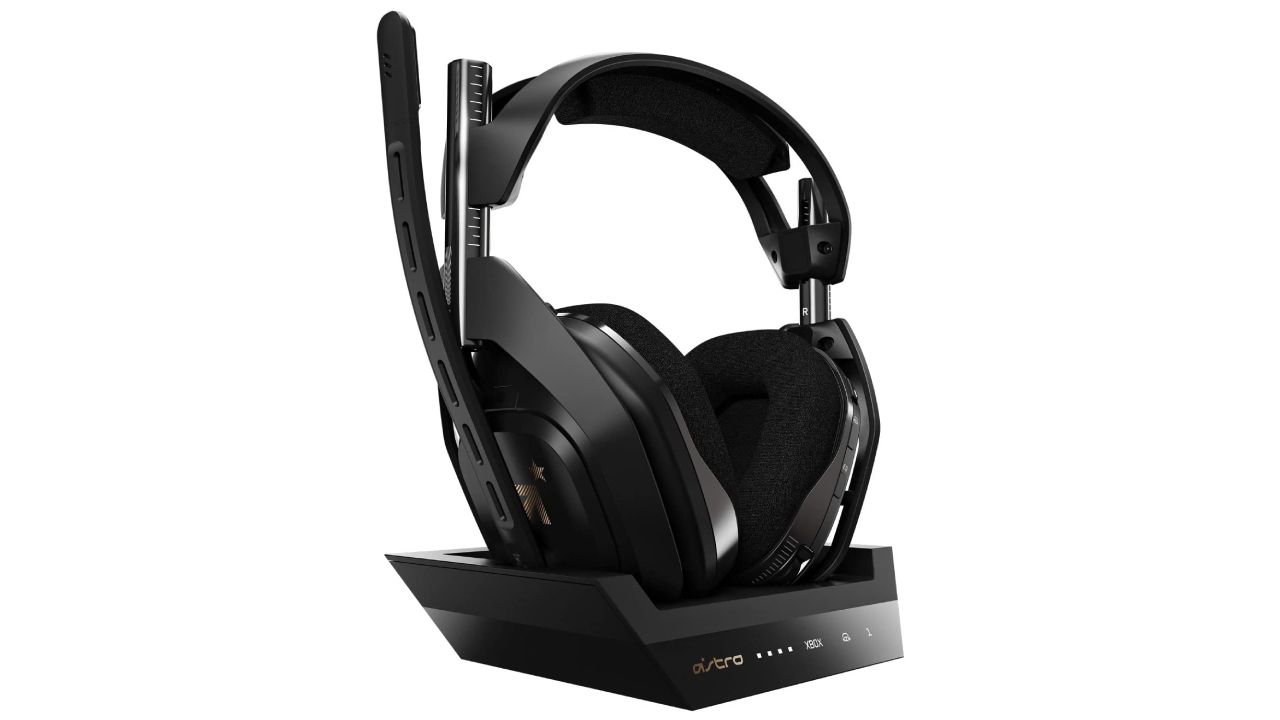 ASTRO Gaming A50 product image of a black over-ear headset sat on a black stand with gold trim.