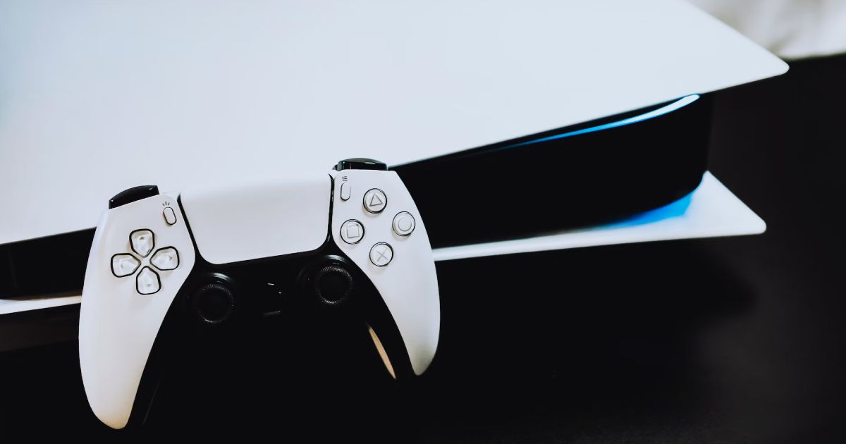 A black and white DualSense controller leaning against a horizontal PS5.