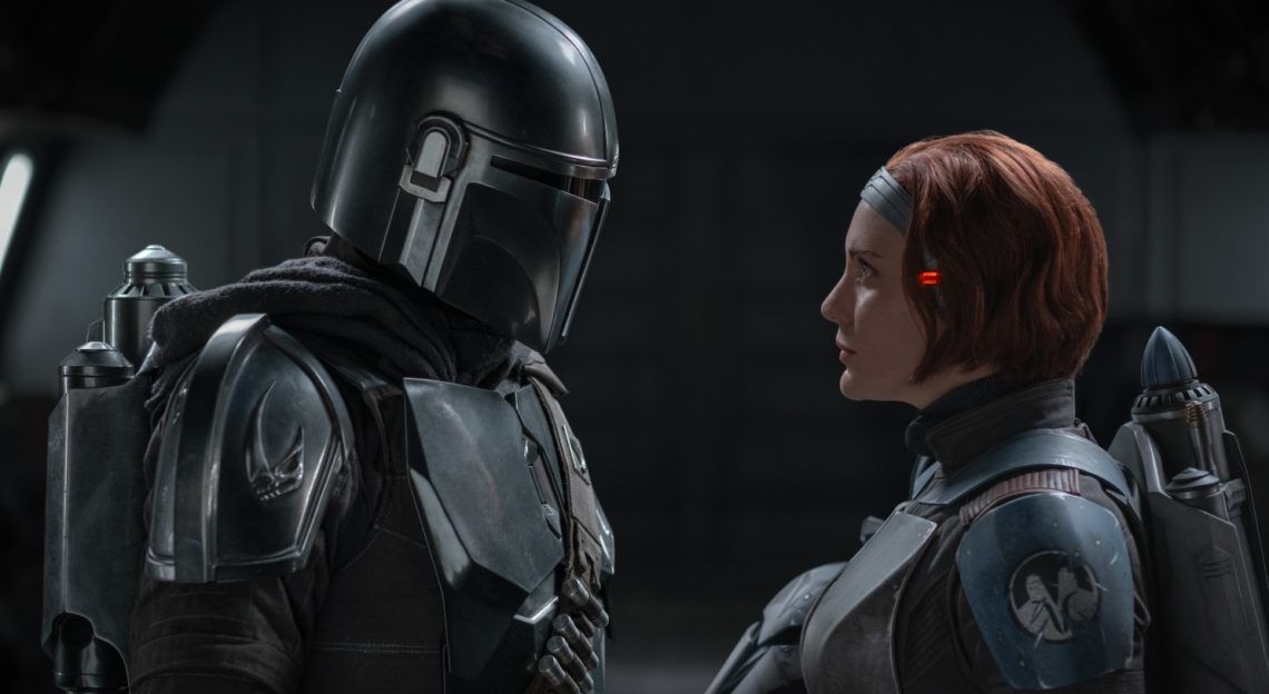 Bo-Katan and Din Djarin are looking at each other.