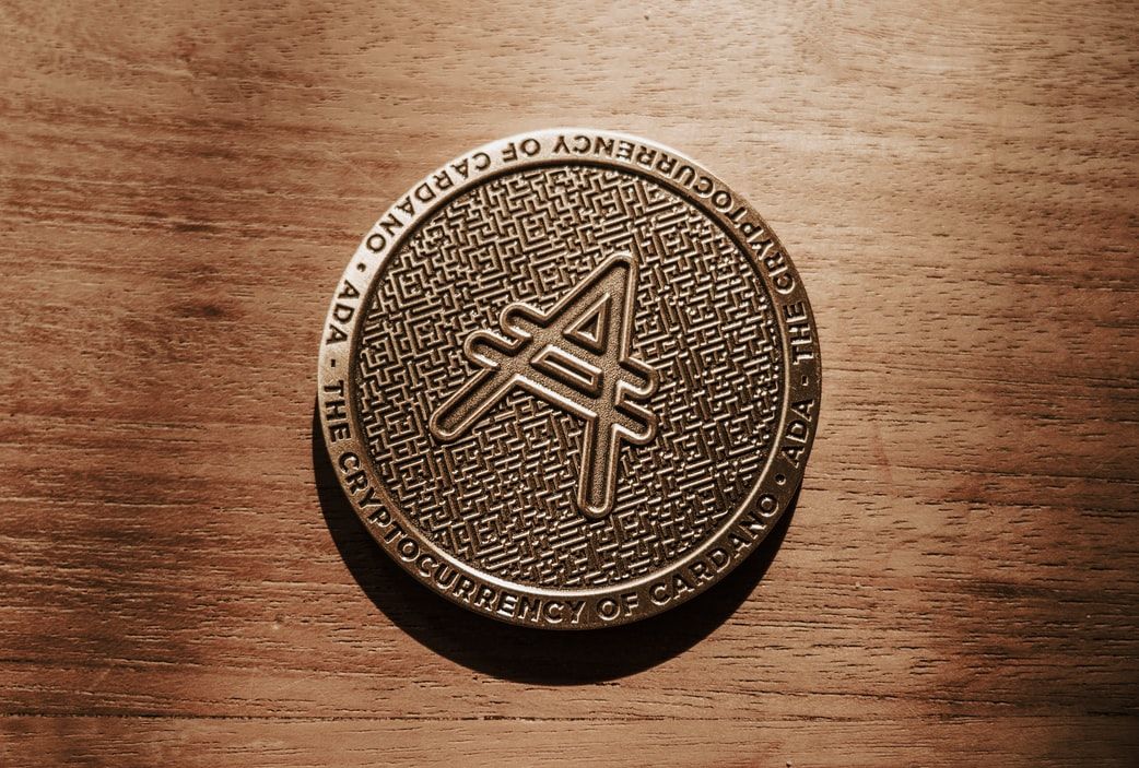 Image of Cardano/ADA coin on a brown, wooden background