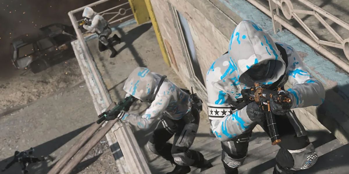 Screenshot of Warzone 2 playhers moving up staircase on the side of a building. All 3 players are holding a submachine gun and wearing a blue and white ranked play hoodie