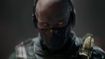 A bald man with glowing orange eyes and a black mask covering his mouth and nose