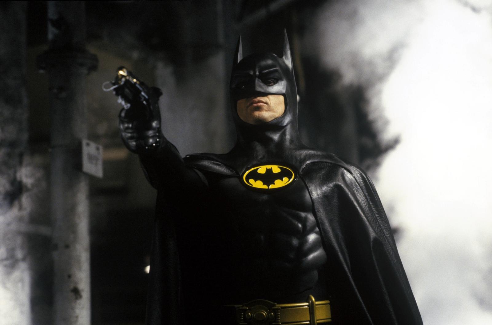 The Batman holds a gun amidst white smoke.
