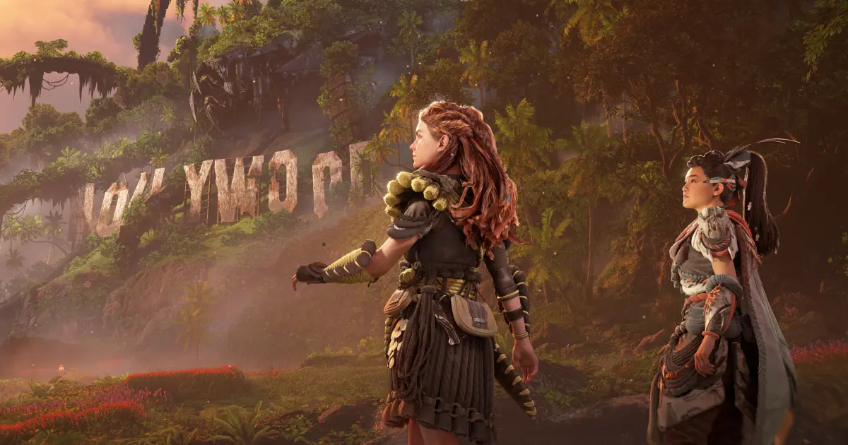 Aloy in Horizon Forbidden West in her warrior gear next to another character with the post-apocolypse Hollywood sign in the background.