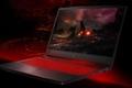 A black gaming laptop with a dark fiery scene on the display and red backlit keys.