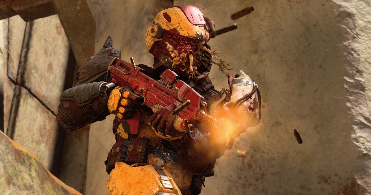 An orange-armoured character in Halo firing a red gun.