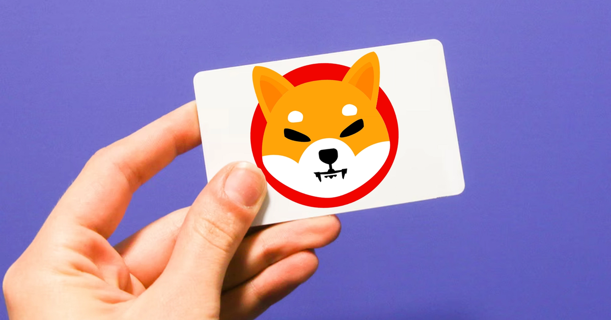 Shiba Inu logo on a card, held by a hand against a purple background, after a SHIB whale bough $250,000 worth of gift cards.