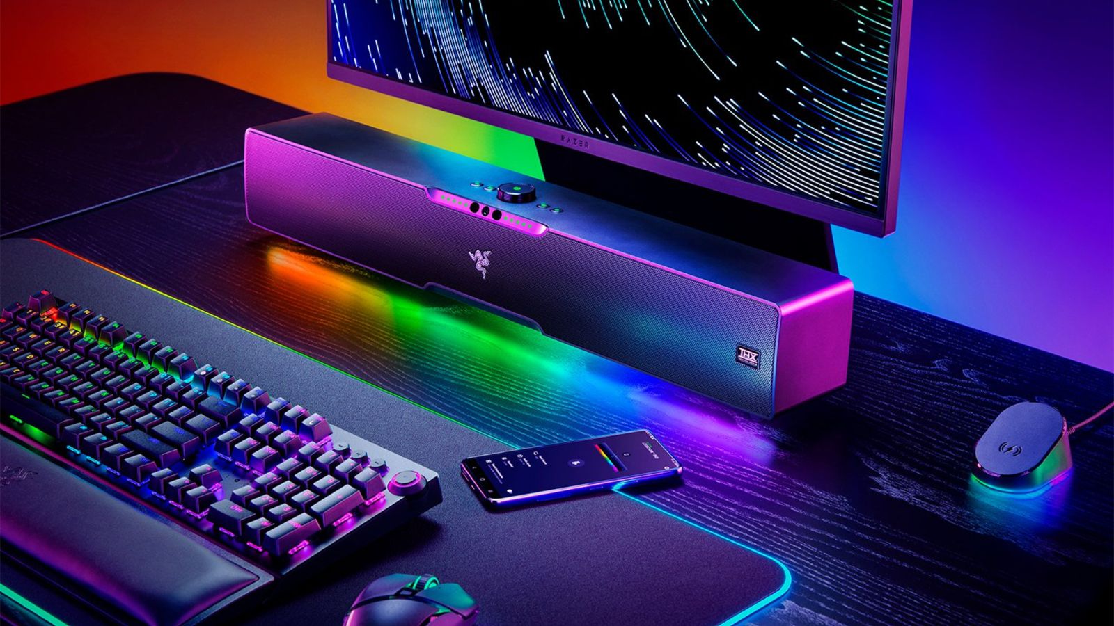 Best soundbar for gaming - Razer Leviathon V2 Pro product image of a black soundbar surrounded by RGB lighting sat at a desk with a monitor, keyboard, and mouse.