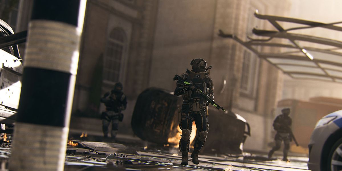 Screenshot of Warzone players patrolling war torn street with burning vehicle in background