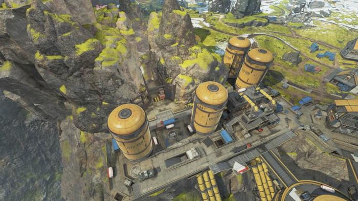 An overhead shot of huge silos, with a narrow cavern running through a mountain behind them.