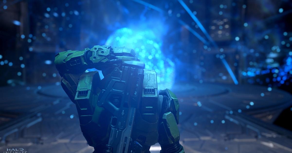 Master Chief stands in front of a giant blue orb of light.