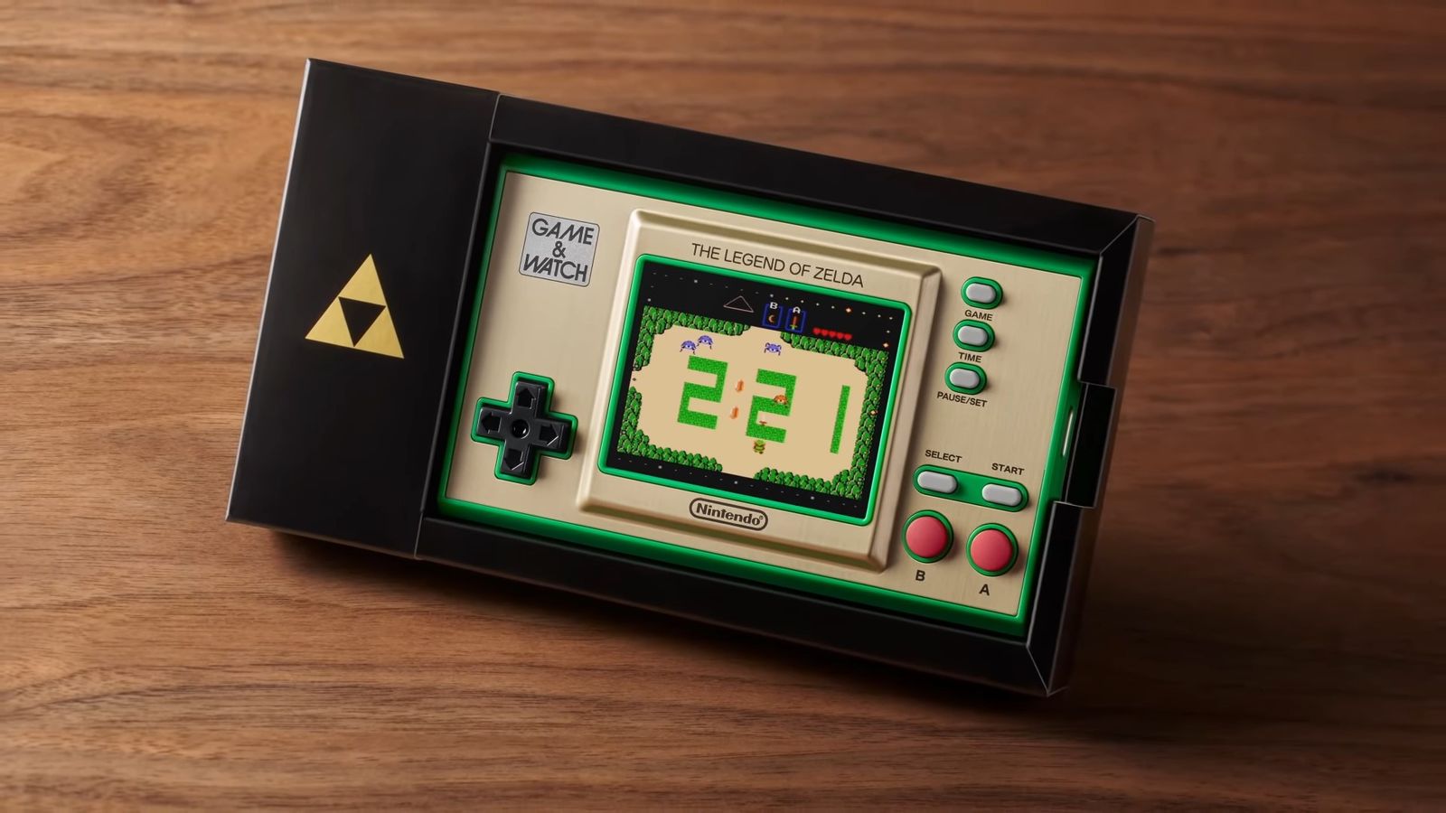 The Game & Watch: the Legend of Zelda handheld sits in its black dock, on a darkwood surface