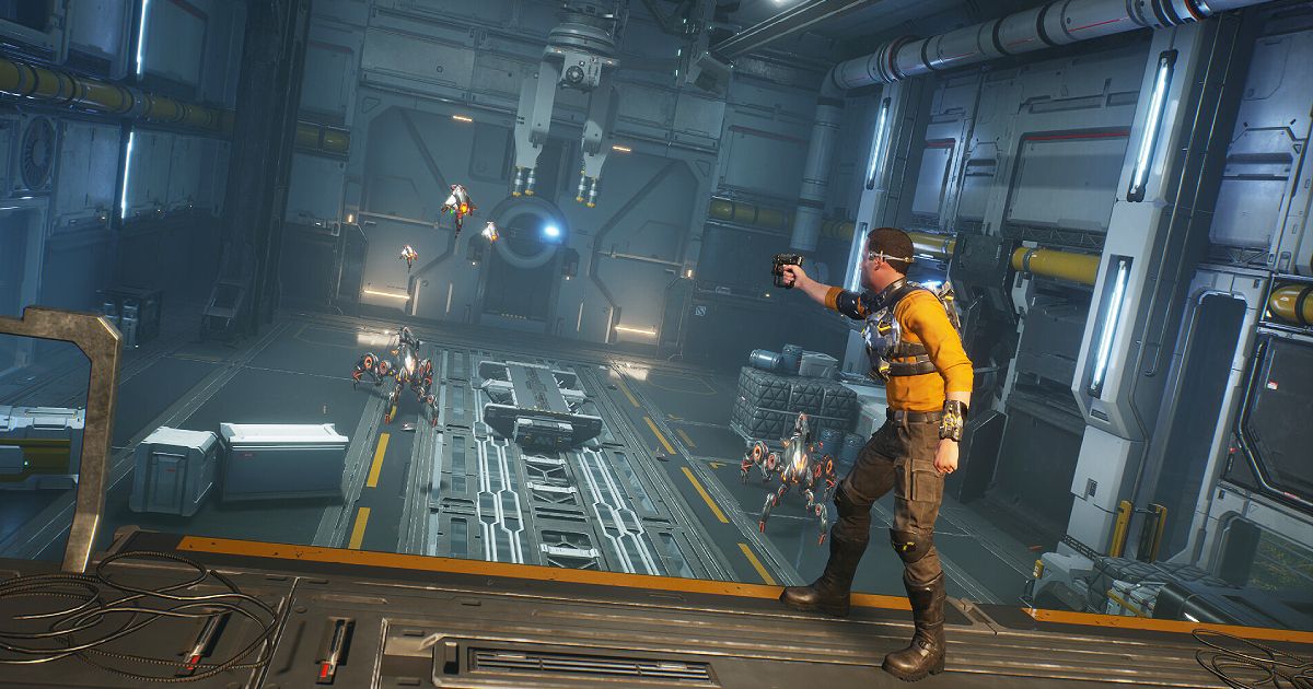 Cutter Slade in a yellow shirt firing at robots in a Sci-Fi hanger.