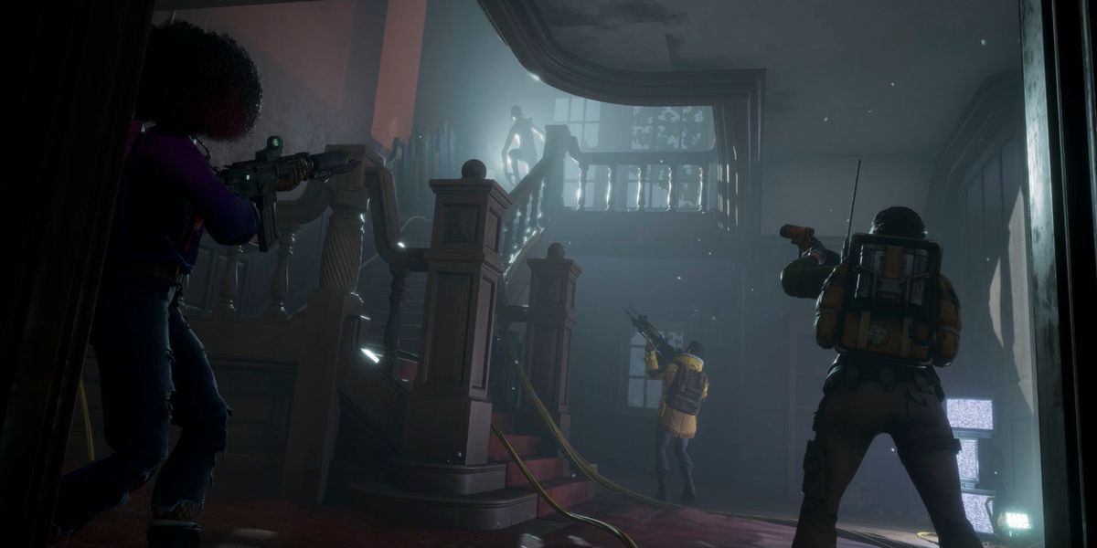 Screenshot of Redfall players standing at the bottom of a dark staircase holding their guns