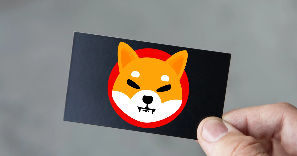 Thumb holding a black gift card with the Shiba Inu Logo.