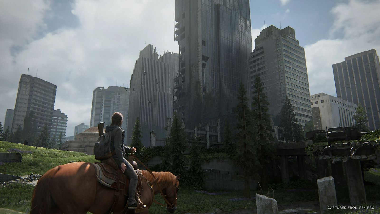 Ellie on a horse and looking at a derelict city in The Last of Us Part 2.