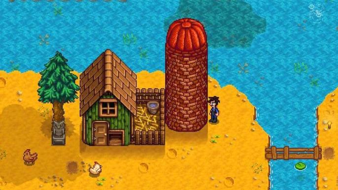 Stardew Valley. The player is stood next to a silo and their coop. The player is on the right of the screen and looking at the tall brick silo on their left. 