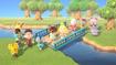 In-game image from Animal Crossing of a collection of characters standing either side of a river, with Tom Nook and Isabelle standing on a bridge.