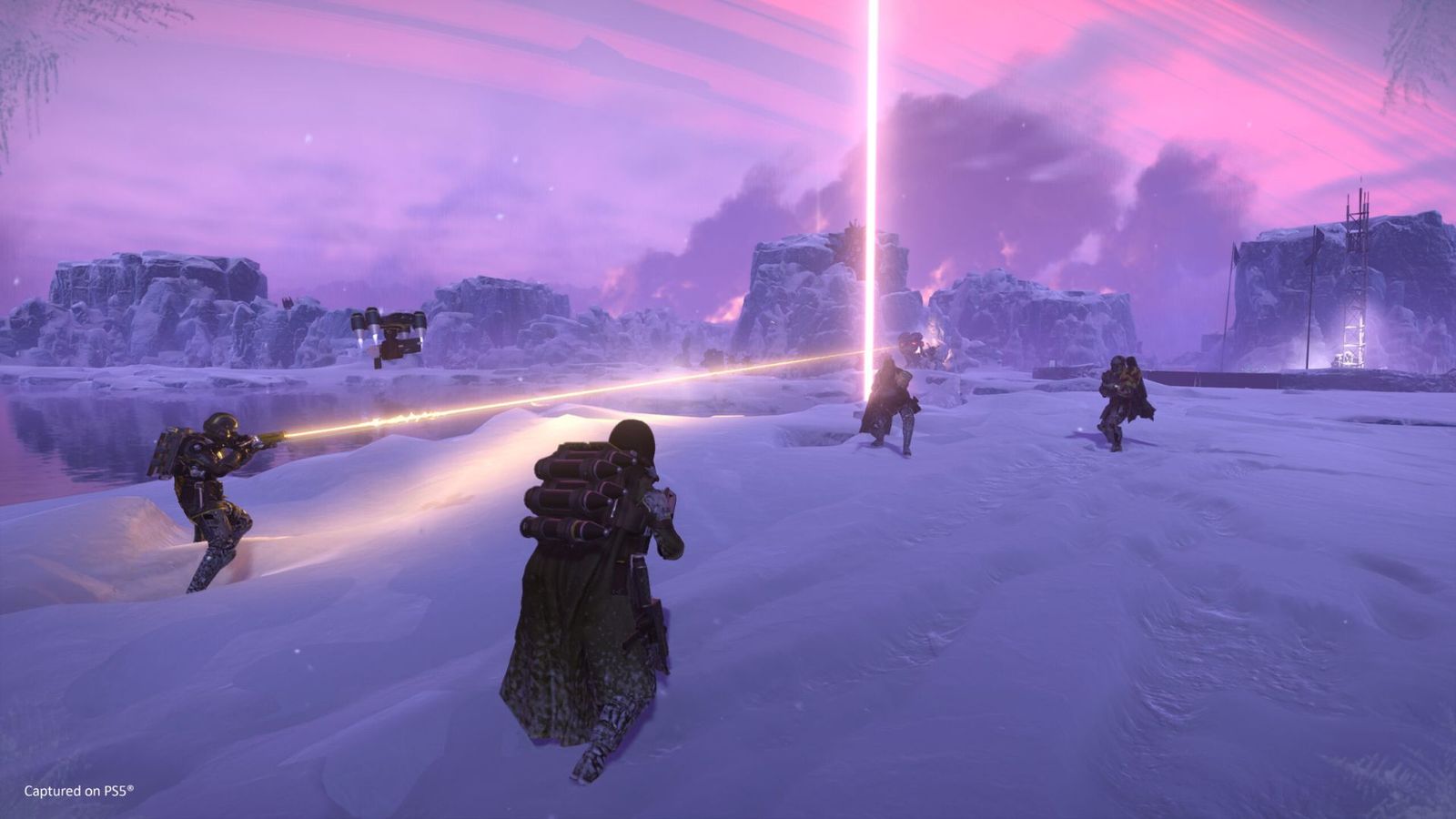 Helldivers 2 player standing in snow with teammates and light beams in background