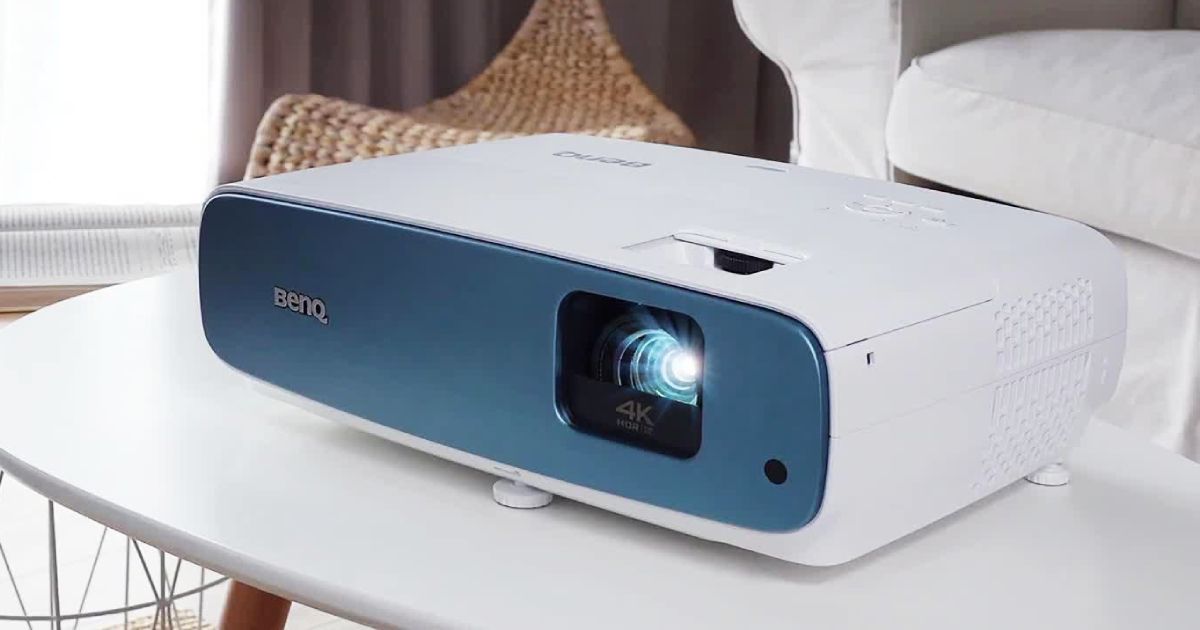 A white projector with with a blue front panel sat on a white table.