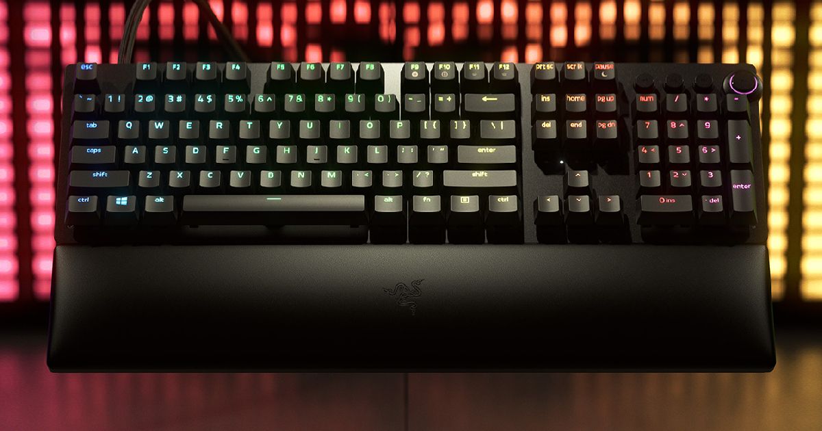 A black wired gaming keyboard featuring multicoloured backlit keys and a wrist rest at the front.