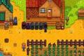 Stardew Valley. The player is facing one of their four furnaces that are lined up by their house. Crops can be seen in a rectangular formation on the lower half of the screen. The four furnaces are black and lined up in front of the main house. On the left of the screen there is a small house with a green roof. 
