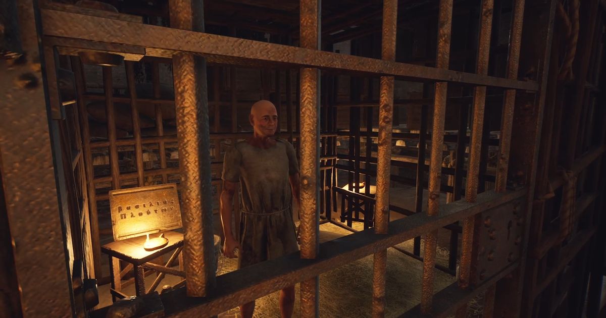 The Forgotten City. The prisoner (Duli) is inside his cell. A tablet can be seen to the left of Duli who is standng in the middle. There are steel bars across the front of the image.