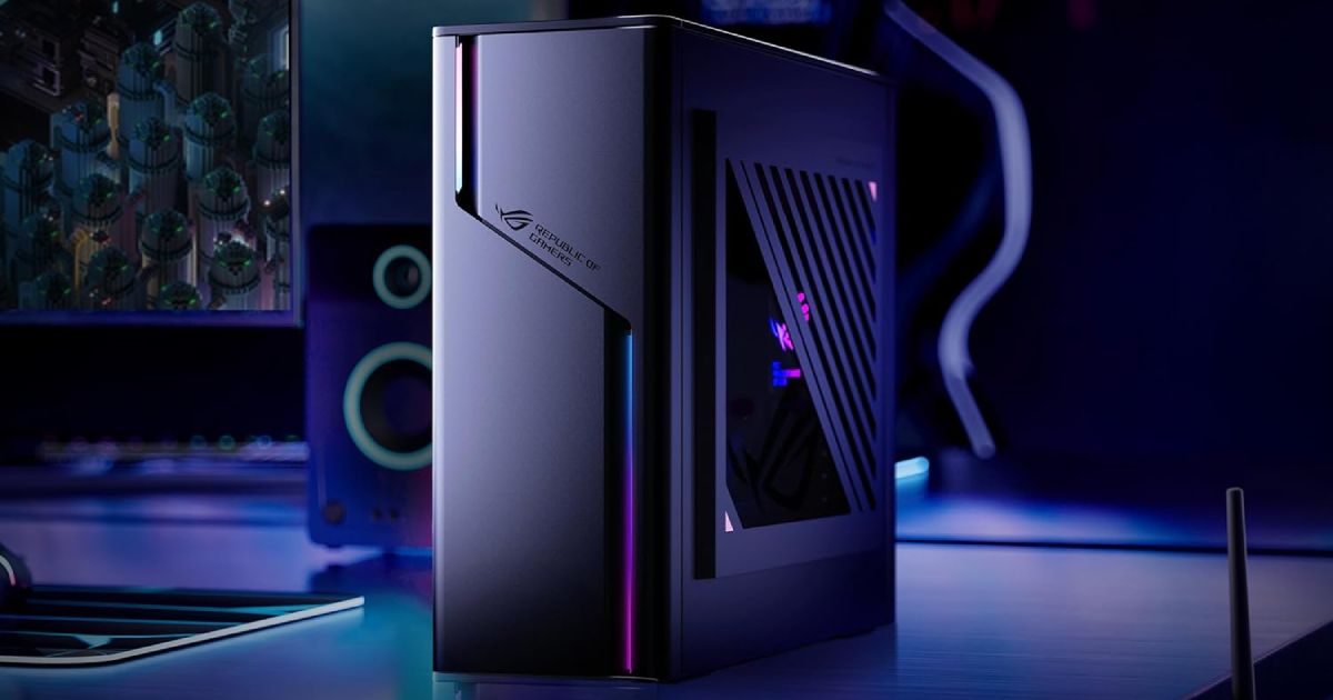 A dark grey desktop gaming PC featuring blue, purple, and pink lighting to match the surrounding room lighting.
