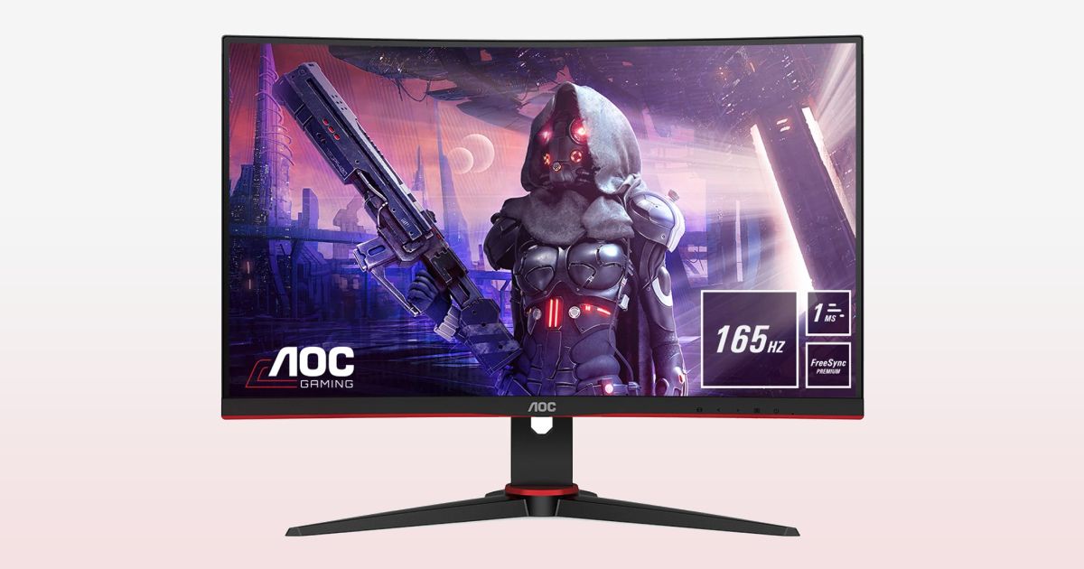 A black near-frameless gaming monitor with red trim and a robot with red eyes on the display in front of a gradient white and orange background.