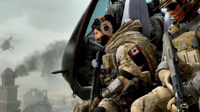 Screenshot of Warzone 2 players sitting on the side of a helicopter flying over a smoking building