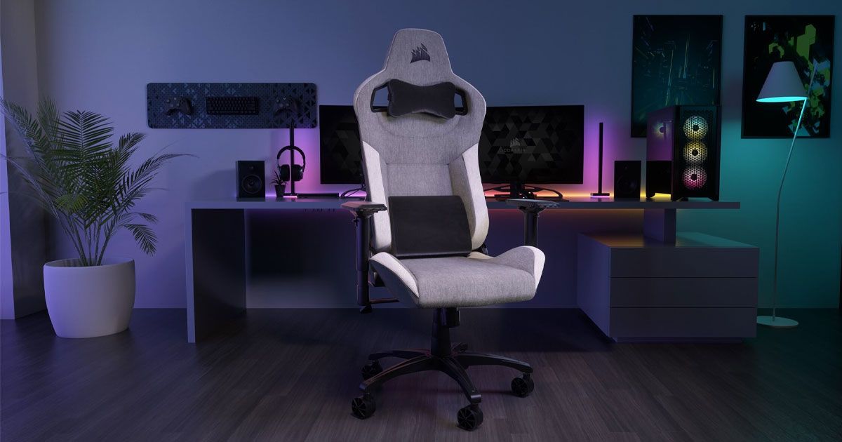 A grey fabric gaming chair with black and white trim in front of a PC gaming setup.