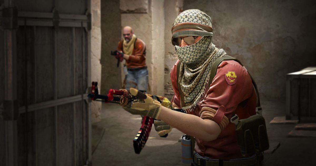 A character in CS:GO wearing a red top and a scarf around their face holding a riffle.