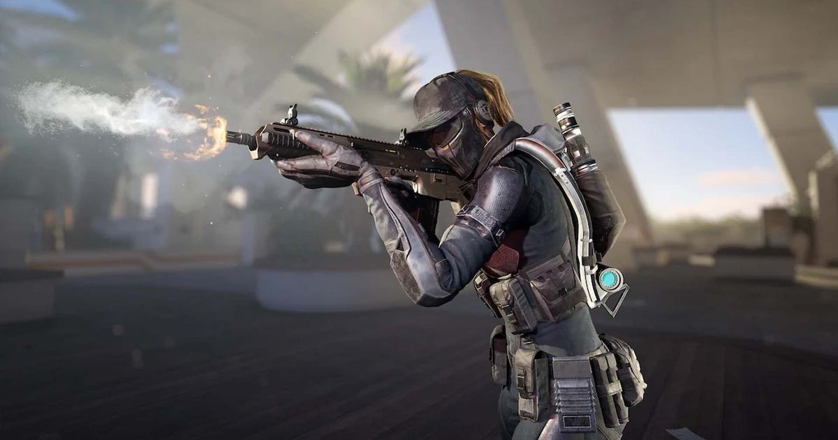 Screenshot of XDefiant player firing assault rifle and aiming down sights with blue sky and a palm tree in the background