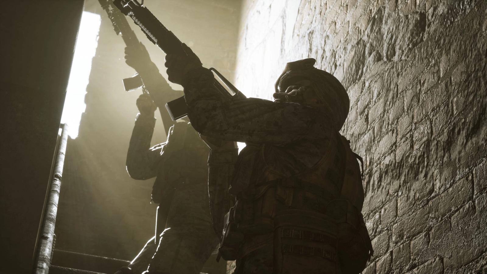 A screenshot from Six Days in Fallujah. Two armed military men are walking upstairs in a basic stone building. Their guns are pointed in unison, anticipating a threat.