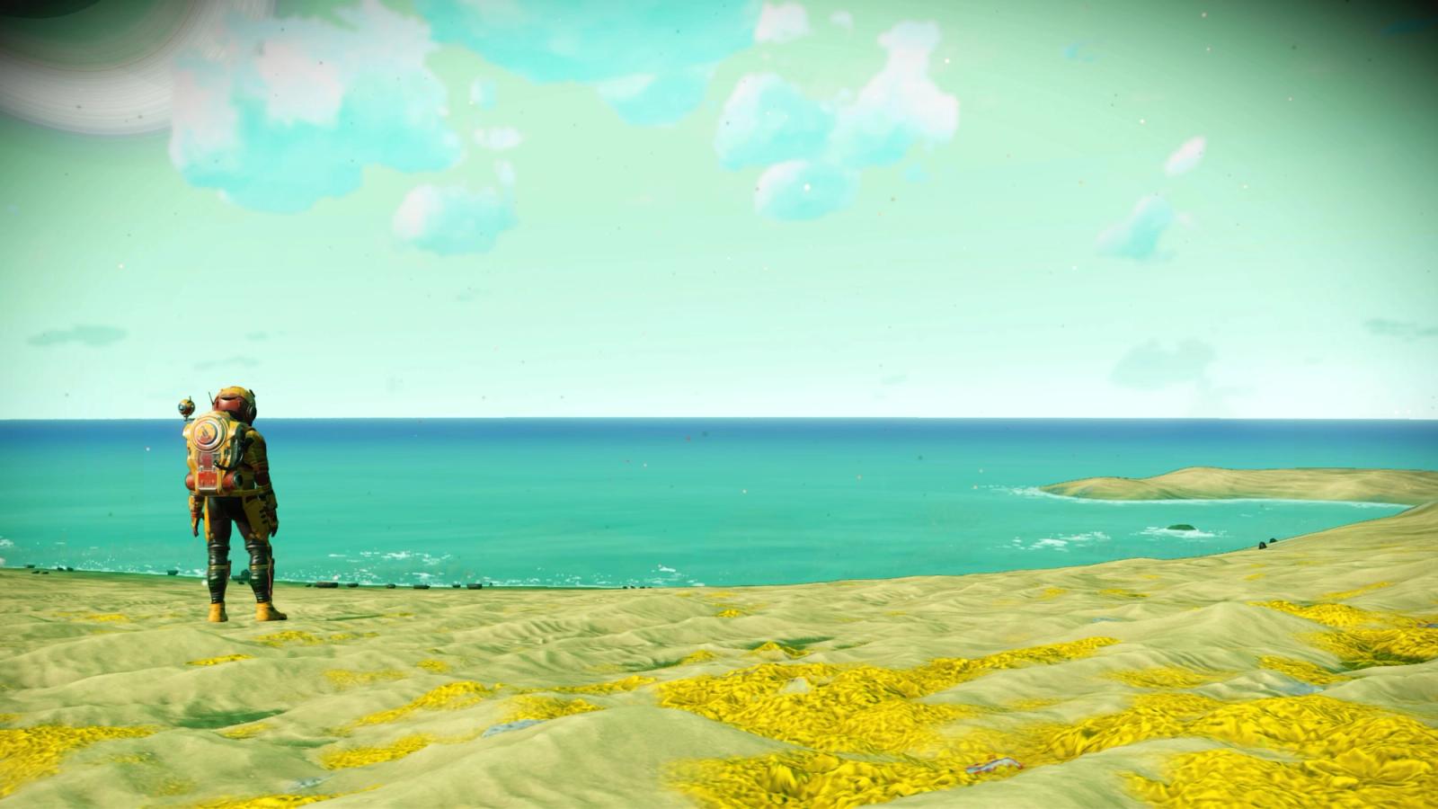 A screenshot from No Man's Sky featuring a character in a space suit, standing on a beach, and overlooking the water.