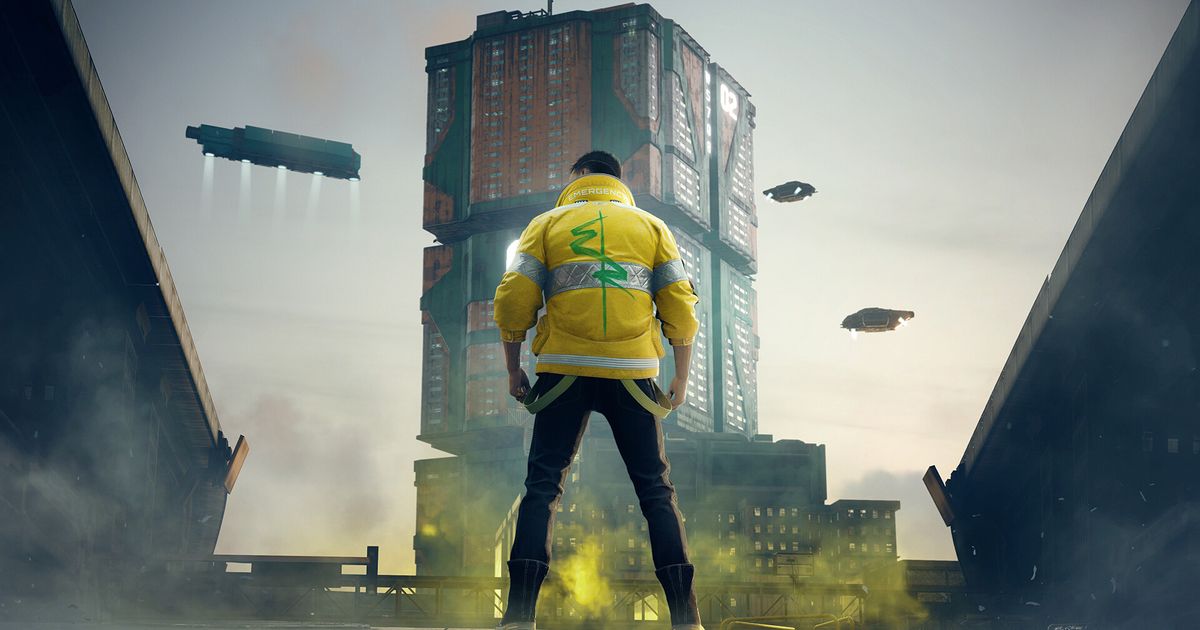 A man in a yellow jacket is standing in front of a city building.